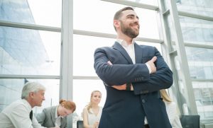 Confident businessman standing in front of sitting coworkers